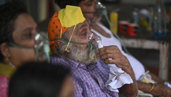 Pacientes de coronavirus respiran con la ayuda del oxígeno proporcionado por un Gurdwara, un lugar de culto para los sijs, en una carpa instalada a lo largo de la carretera de Ghaziabad, en la India. (Foto de Sajjad HUSSAIN / AFP).