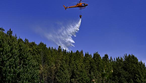 Un helicóptero arroja agua para apagar un incendio forestal en Nemocón, Colombia, el 26 de enero de 2024. (Foto de Luis ACOSTA/AFP)