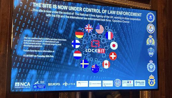 Una pantalla de televisión en el frente del sitio de filtración de la web oscura de LockBit que fue reemplazada con las palabras "este sitio ahora está bajo control de las fuerzas del orden", junto con las banderas del Reino Unido, los EE. UU. y varias otras naciones. (Foto: AP/Kelvin Chan)