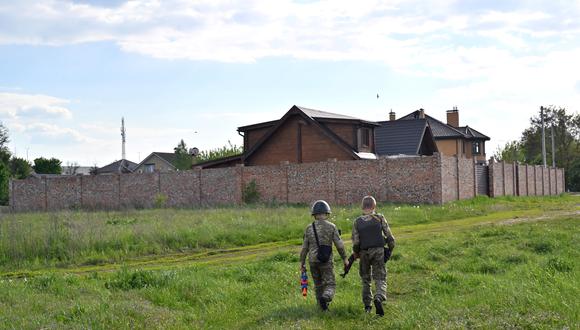 Andriy Shyrokyh (derecha), de 13 años, y Maksym Mudrak (izquierda), de 10 años, vestidos con uniforme de combate y chalecos antibalas caseros, juegan un juego de guerra en la aldea de Stoyanka, en la región de Kiev, que fue ocupada por tropas rusas. (Foto de Serguéi SUPINSKY / AFP)