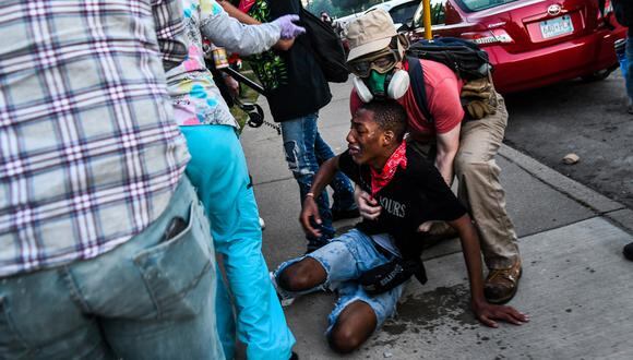 Un hombre recibe asistencia después de ser alcanzado por gases lacrimógenos cerca del quinto recinto policial durante una manifestación para pedir justicia para George Floyd, un hombre afroamericano que murió mientras estaba bajo custodia de la policía de Minneapolis. (Foto: AFP/CHANDAN KHANNA)