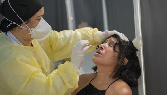 Una mujer recibe un hisopo nasal para una prueba rápida de COVID-19 en un centro médico comunitario en Sao Paulo, Brasil. (Foto: AP/ Andre Penner).