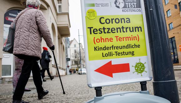 Una mujer pasa frente a un centro de pruebas de coronavirus (covid-19) en la ciudad de Halle/Saale, este de Alemania, el 25 de enero de 2022. (JENS SCHLUETER / AFP).