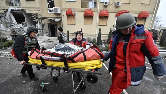 Médicos ucranianos llevan el cuerpo de un residente local asesinado en un edificio residencial después de un bombardeo ruso en Kherson, en el sur de Ucrania, el 29 de enero de 2023, en medio de la invasión rusa de Ucrania. (Foto de Genya SAVILOV / AFP)