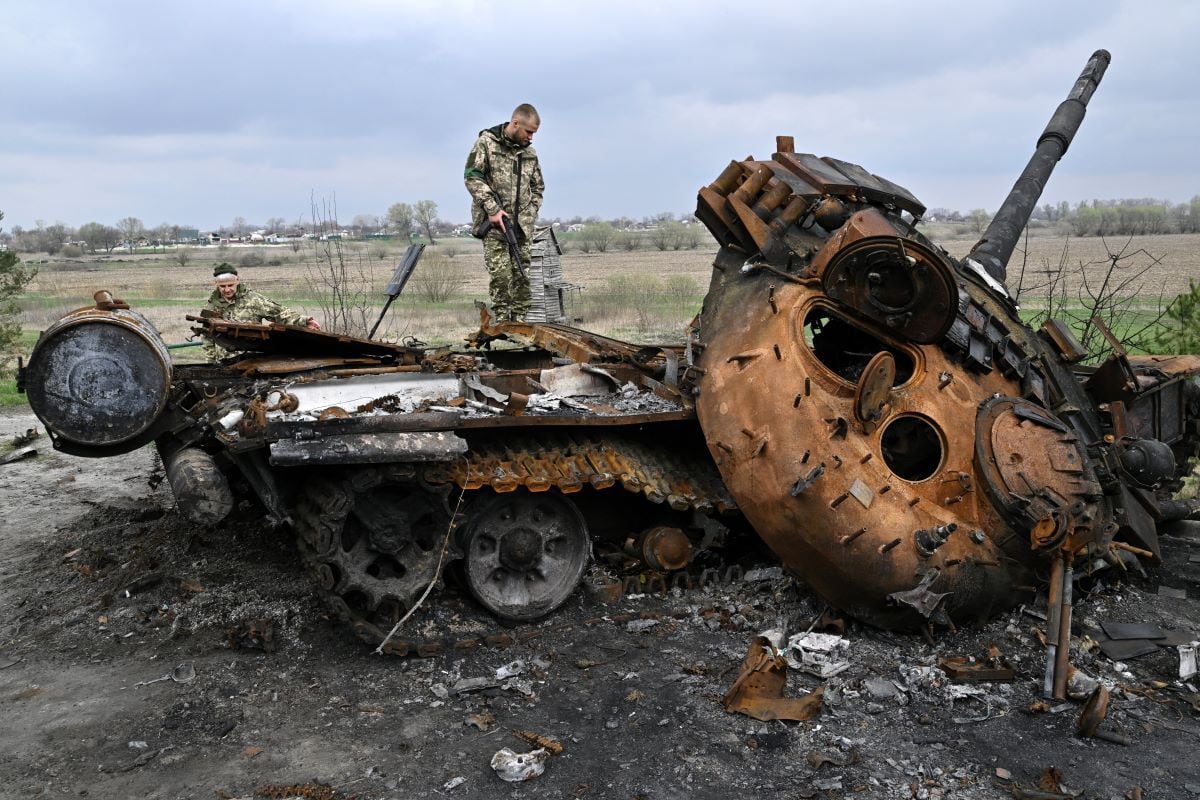 Ukrainian servicemen look at a destroyed Russian tank on a road in the village of Rusaniv, in the kyiv region, on April 16, 2022. (Genya SAVILOV / AFP)