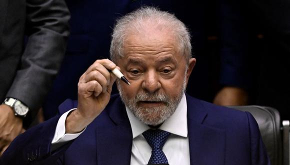 El nuevo presidente de Brasil, Luiz Inácio Lula da Silva, muestra un bolígrafo que le regalaron en 1989 mientras firma el documento de toma de posesión durante su ceremonia de investidura en el Congreso. (MAURO PIMENTEL / AFP).