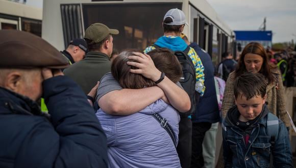 Refugiados se abrazan tras llegar al estacionamiento de un centro comercial en Zaporiyia (Ucrania). (EFE/ MIGUEL GUTIÈRREZ)