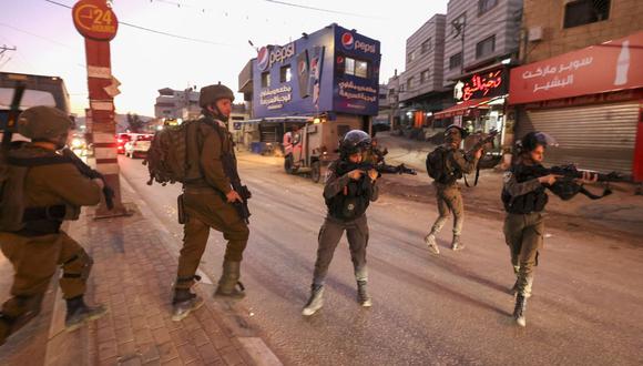 Las fuerzas de seguridad israelíes apuntan sus armas mientras se despliegan en la ciudad ocupada de Hawara, en Cisjordania, luego de un incidente durante el cual, según informes, la policía israelí mató a tiros a un palestino, el 2 de diciembre de 2022. (Foto de Jaafar ASHTIYEH / AFP)