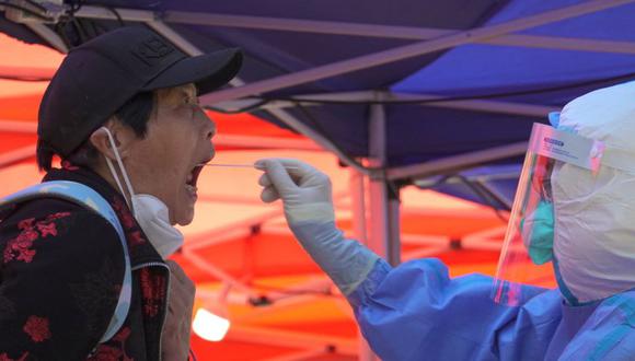 Un trabajador médico con traje protector recolecta una muestra de hisopo de una persona durante una prueba masiva de la enfermedad por coronavirus en medio de un brote, en un sitio de prueba improvisado en el distrito de Chaoyang de Beijing, China.
