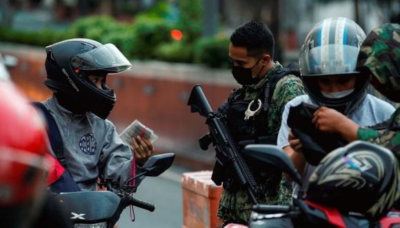 Un oficial de policía revisa la tarjeta de identificación de un motociclista en un puesto de control en el límite de Quezon City y Manila en Metro Manila, Filipinas. (Foto: EFE / EPA / MARK R. CRISTINO).