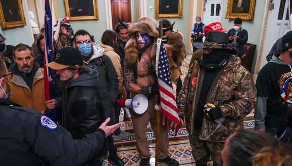 Jake Angeli (C), un partidario de QAnon conocido por su cara pintada y su sombrero con cuernos, ingresan al Capitolio el 6 de enero de 2021 en Washington, DC. (Foto de Saúl LOEB / AFP)