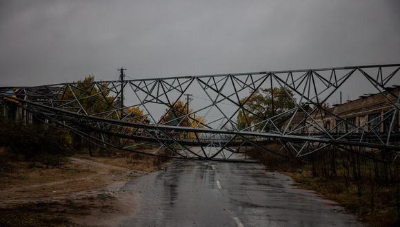 Esta fotografía tomada el 26 de octubre de 2022 muestra una torre de electricidad destruida que bloquea una calle de la aldea ucraniana recientemente recuperada de Yampil, en el este de Ucrania. (Dimitar DILKOFF / AFP).