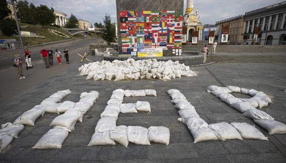 Personas caminan junto a un mensaje que pide ayuda al mundo, escrito con sacos de arenas, en la plaza Maidán, Kiev. (EFE/ Orlando Barría)