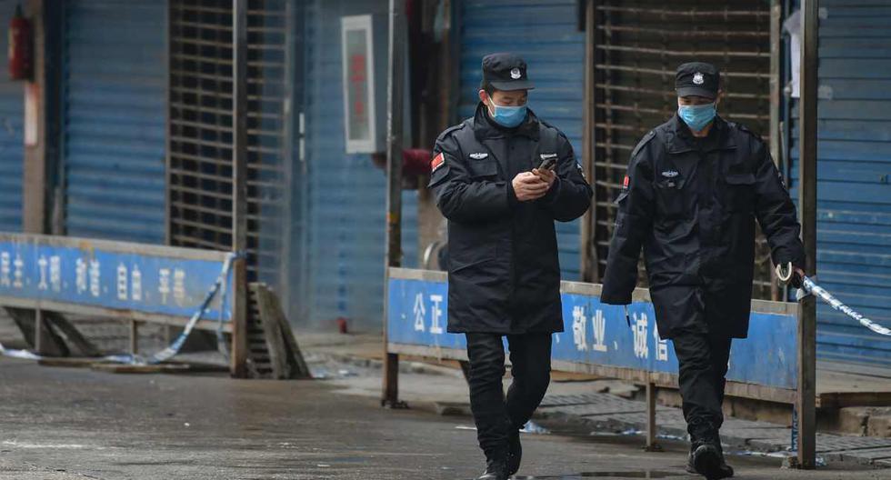 Coronavirus en China | Efectivos de seguridad, con sus respectivas máscaras para prevenir contagios, patrullan zona de mercado de productos marinos Huanan, en Wuhan, China. (Foto: Hector RETAMAL / AFP)
