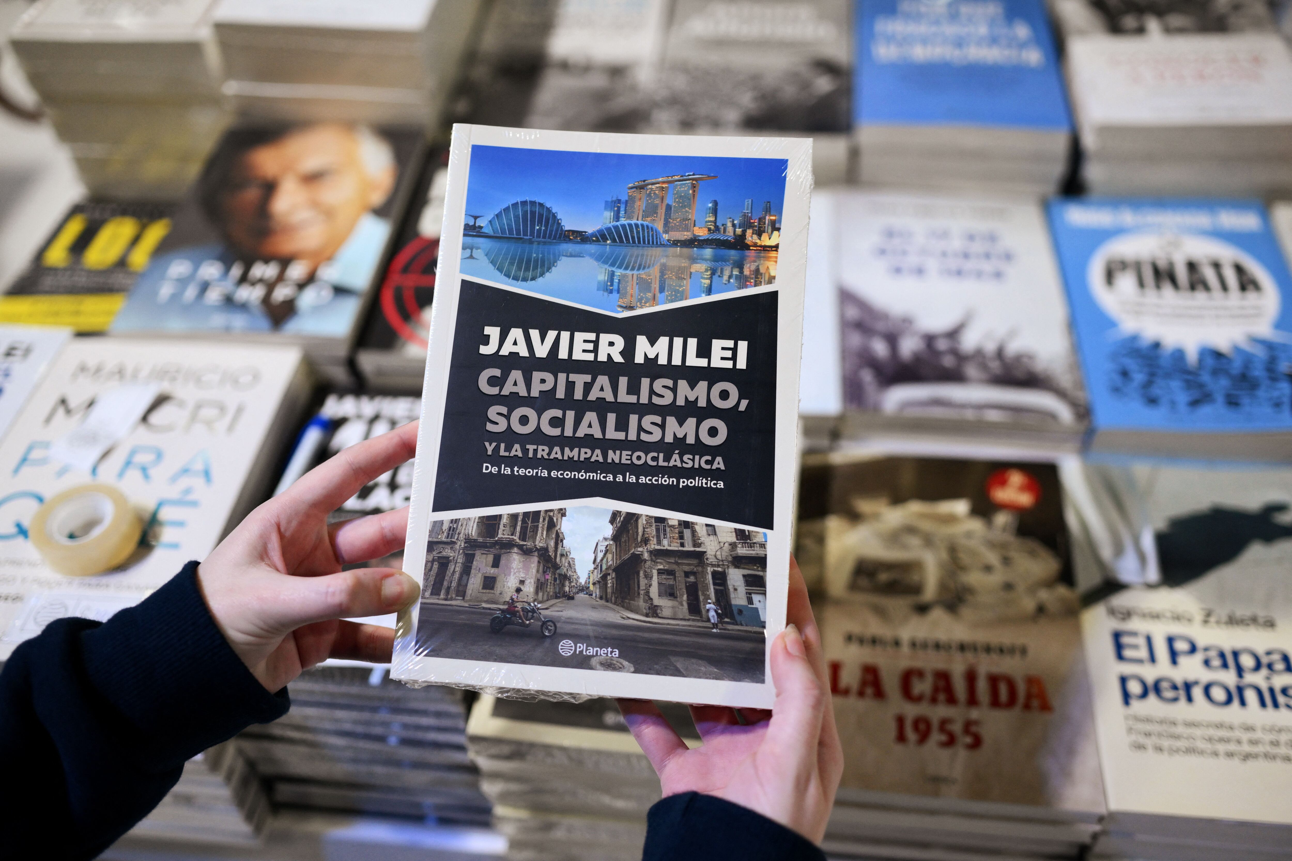 Una mujer toma una copia del libro del presidente Javier Milei en la 48 Feria Internacional del Libro de Buenos Aires el 25 de abril de 2024. (Foto de Luis ROBAYO/AFP).