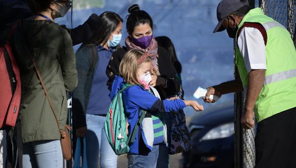 Imagen referencial. A una niña le revisan la temperatura antes de ingresar a su colegio, en Quito. 13 de setiembre del 2021. AFP