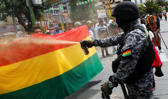 Un miembro de las fuerzas de seguridad de Bolivia usa gas pimienta contra manifestantes que protestan en La Paz contra la reelección de Evo Morales. (REUTERS / Kai Pfaffenbach).