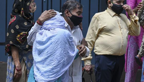 Los familiares lloran mientras esperan recibir el cuerpo de su ser querido, que murió debido al coronavirus, en una morgue en Nueva Delhi (India), el 21 de mayo de 2021. (Prakash SINGH / AFP).