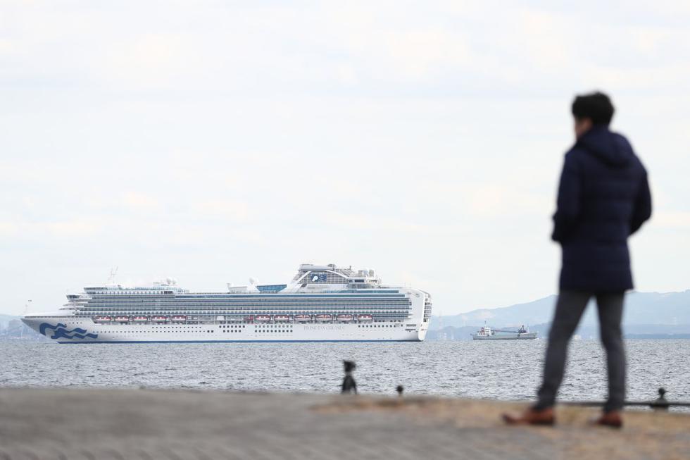 Un periodista japonés mira hacia el crucero Diamond Princess con más de 3.000 personas abordo mientras se encuentra anclado en cuarentena frente al puerto de Yokohama un día después de que llegó con pasajeros sintiéndose enfermos. (AFP)