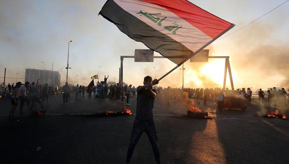 Un manifestante iraquí ondea la bandera nacional durante una manifestación contra la corrupción estatal, el fracaso de los servicios públicos y el desempleo. (Foto: AFP)