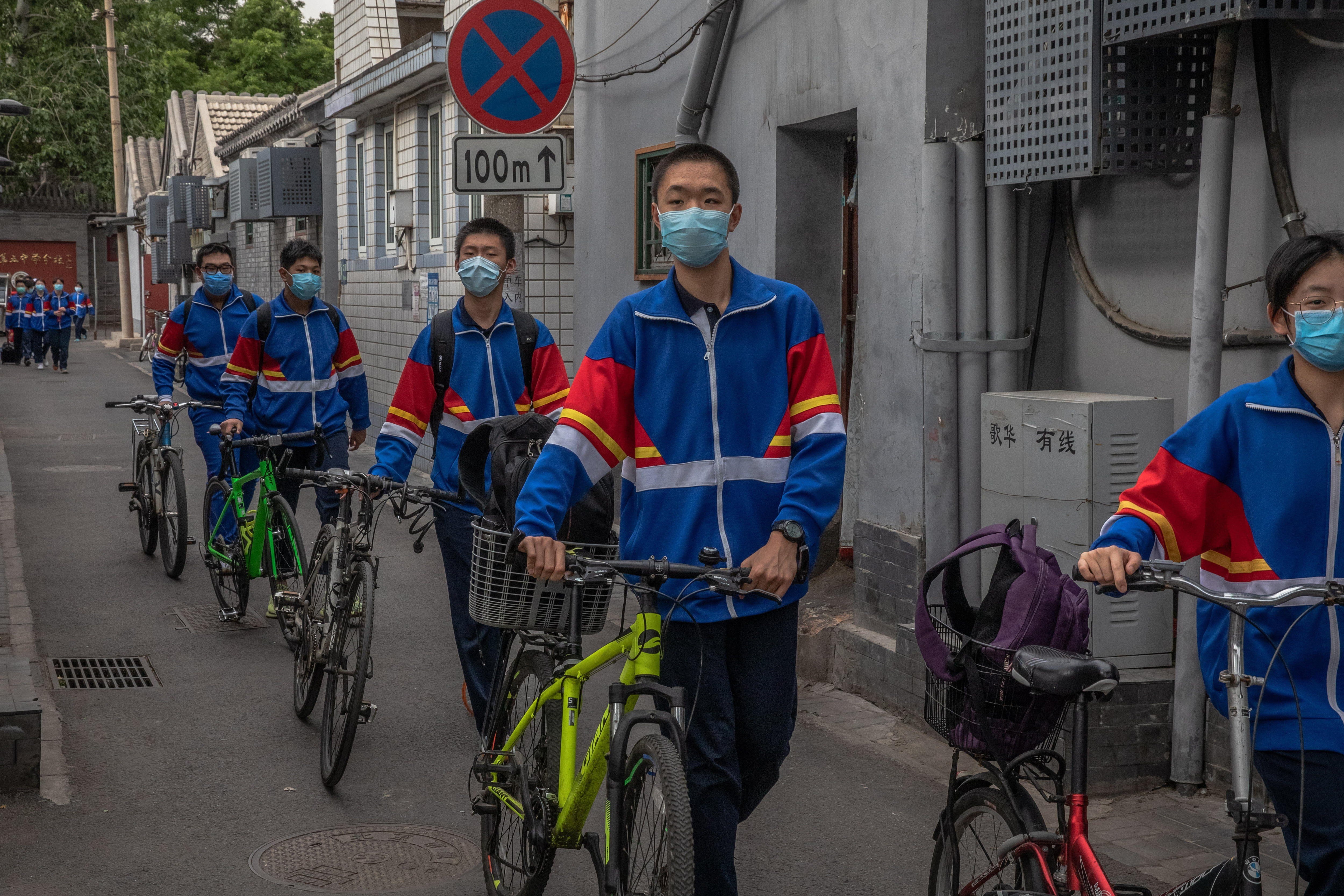Estudiantes que usan mascarillas protectoras salen de su escuela secundaria en su primer día de clases tras el confinamiento por coronavirus en Beijing. (EFE / EPA / ROMAN PILIPEY).