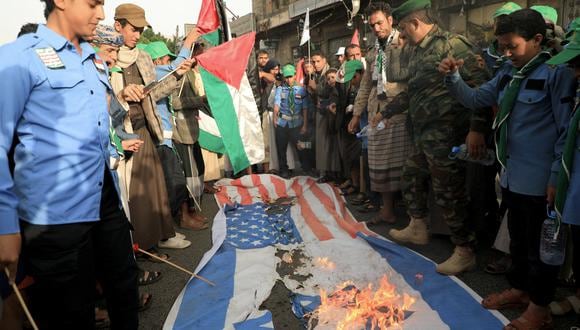 La gente prendió fuego a una bandera de Israel y a una de Estados Unidos en las calles de Saná, la capital de Yemen, controlada por los hutíes, el 7 de octubre de 2023, durante una manifestación en apoyo de los palestinos. (Foto de MOHAMMED HUWAIS / AFP)