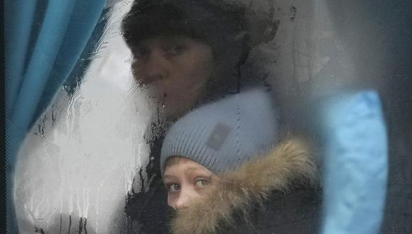 Una mujer y un niño miran por la ventana de un autobús cuando salen de Sievierodonetsk, en la región de Lugansk, en el este de Ucrania, el jueves 24 de febrero de 2022. (Foto AP/Vadim Ghirda).