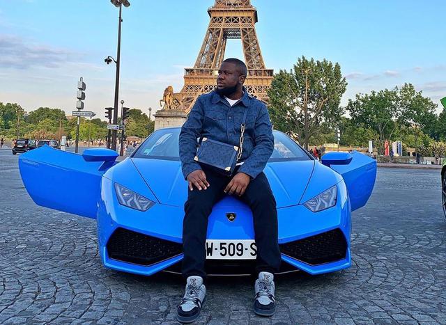Raymond Igbalode Abbas, conocido en Instagram como Hushpuppi, posa sobre uno de sus automóviles frente a la Torre Eiffel. (Foto: Instagram @hushpuppi)