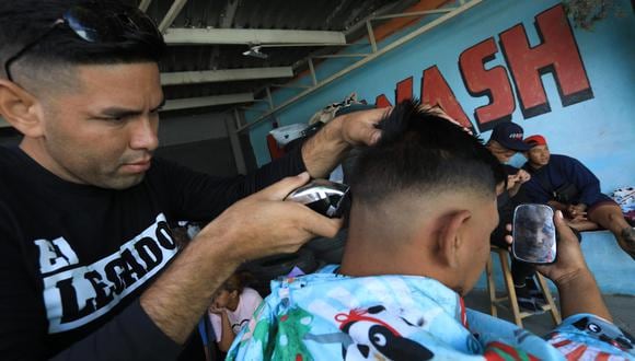 El migrante de origen venezolano José Miguel Ceballos corta el cabello a una persona el 11 de noviembre de 2022 en Ciudad Juárez, México. (EFE/Luis Torres).