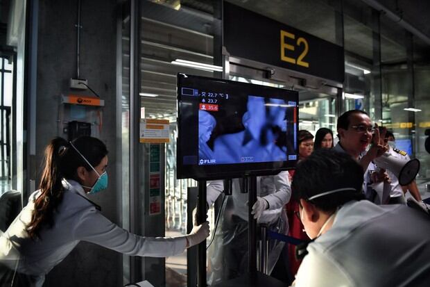 Funcionarios del aeropuerto de Bangkok organizan la pantalla de los escáneres térmicos en el área de llegada de pasajeros (Foto: AFP)