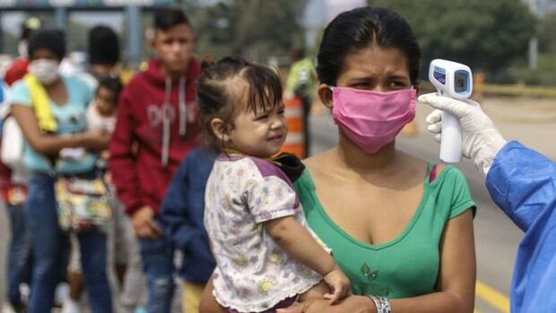 Empleados sanitarios miden la temperatura de los venezolanos que regresan al país desde Colombia, como medida preventiva contra la propagación del coronavirus. (Foto: Schneyder MENDOZA / AFP)