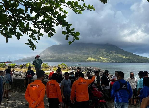 Personas y miembros de la Agencia Nacional de Búsqueda y Rescate observan el humo y las cenizas que brotan del Monte Ruang. (EFE/EPA/BASARNAS).