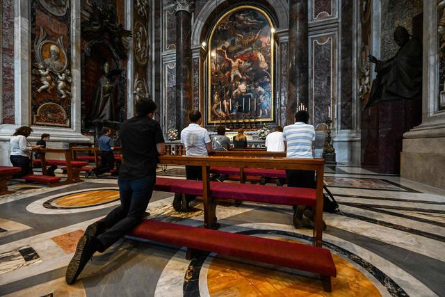 La gente reza junto a la tumba del difunto papa Juan Pablo II en el centésimo aniversario de su nacimiento en la Basílica de San Pedro, que había sido cerrada para frenar la propagación del coronavirus. (AFP / Vincenzo PINTO).
