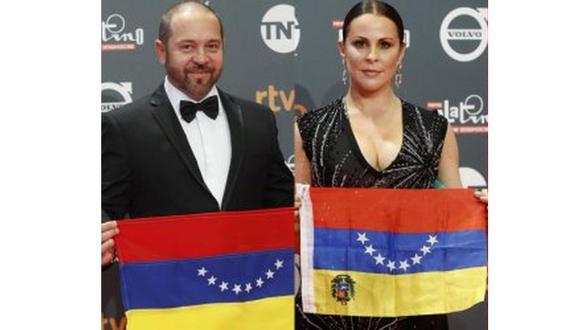 La actriz Malena González (der.) y el actor y director Miguel Ferrari (izq.) posaron con la bandera del país boca abajo. (Foto: AFP)