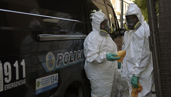 Policías que usan trajes protectores contra el coronavirus desinfectan una camioneta en Buenos Aires, Argentina. (AFP / JUAN MABROMATA).
