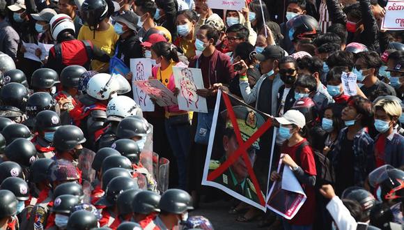 Los manifestantes sostienen un cartel que muestra una foto tachada del jefe de la junta militar, el general Min Aung Hlaing, mientras se enfrentan a la policía antidisturbios durante una protesta en Naypyitaw, Myanmar. (EFE / EPA / MAUNG LONLAN).