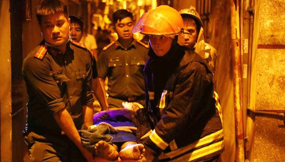 Los rescatistas cargando a las víctimas tras un gran incendio en un bloque de apartamentos en Hanoi. (Foto de STRINGER / Agencia de Noticias de Vietnam / AFP)