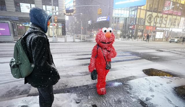 Una persona con un disfraz de Elmo se encuentra bajo la nieve en Times Square en la ciudad de Nueva York la noche del 16 de diciembre. (Foto: TIMOTHY A. CLARY / AFP)