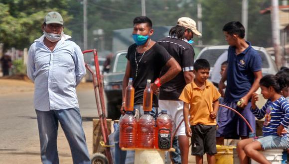 La gente ofrece gasolina a la venta en las calles de Maracaibo, estado de Zulia, Venezuela, en medio de la pandemia de coronavirus COVID-19. (AFP/Luis BRAVO).