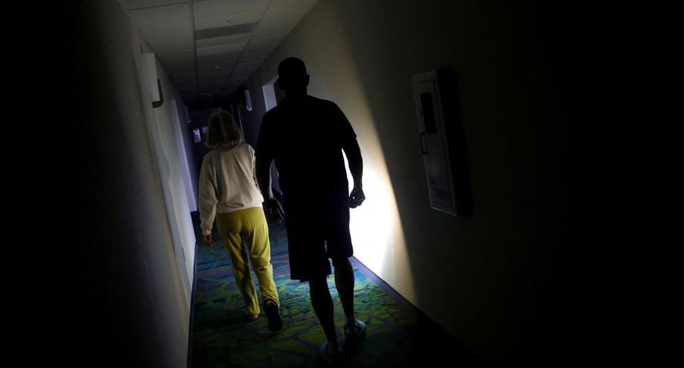 La gente camina en un pasillo usando una linterna durante un corte de energía mientras el huracán Ian toca tierra en el suroeste de Florida. (REUTERS/Marco Bello).