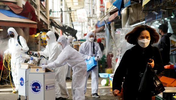 Una mujer con mascarilla camina mientras se produce una fumigación en plena crisis por el coronavirus en Corea del Sur. Foto: Reuters