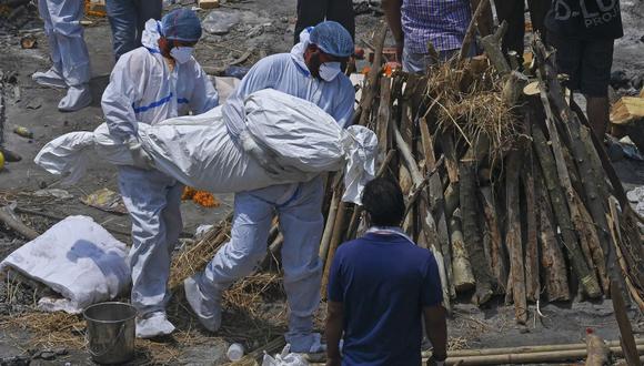 Familiares y trabajadores sanitarios  participan en la cremación de personas fallecidas por coronavirus en la India. (Foto de Prakash SINGH / AFP).