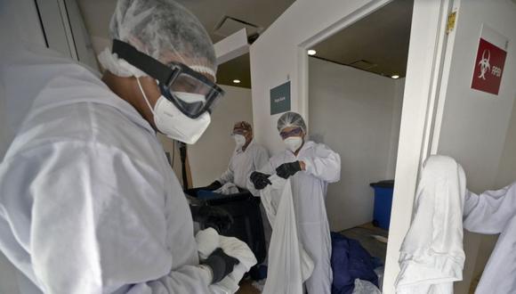 Trabajadores de limpieza recogen ropa contaminada en el hospital del Instituto Mexicano del Seguro Social (IMSS), donde se atienden pacientes con COVID-19, en la Ciudad de México. (Foto: ALFREDO ESTRELLA / AE / AFP)
