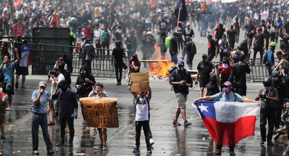 Un manifestante sostiene una bandera que dice "Nueva Constitución" durante una protesta contra el modelo económico estatal de Chile en Santiago. (Foto: Reuters).