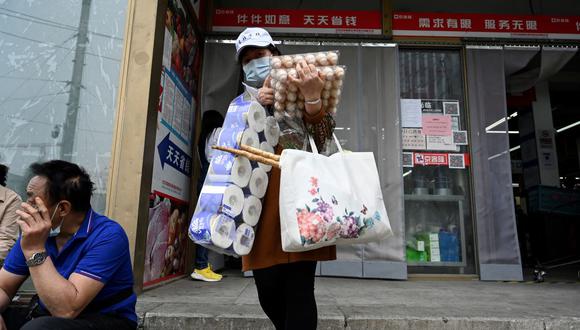Una mujer sale de un supermercado después de comprar alimentos y provisiones para el hogar en Beijing el 25 de abril de 2022, en medio de la pandemia de coronavirus en China. (Jade GAO / AFP).