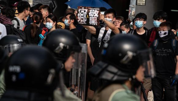 Agentes de policía montan guardia frente a una aldea en el distrito de Yuen Long, mientras la gente asiste a una marcha manifestación que terminó dispándose con gases lacrimógenos contra lo activistas. (Foto: AFP)