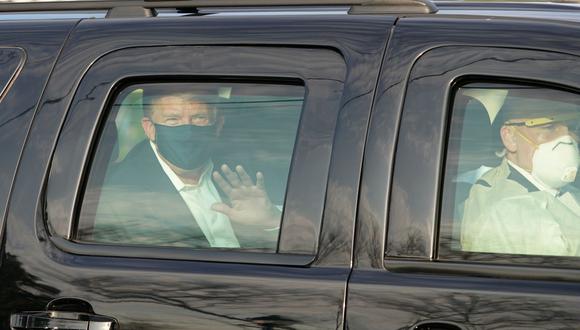 El presidente de Estados Unidos, Donald Trump, saluda desde la parte trasera de un automóvil en una caravana frente al Centro Médico Walter Reed, el 4 de octubre de 2020. (Foto de ALEX EDELMAN / AFP).