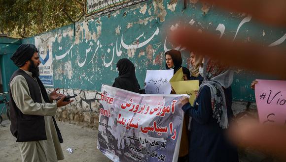 Un miembro del Talibán habla con mujeres manifestantes mientras otro intenta tapar la cámara con la mano durante una manifestación celebrada frente a una escuela en Kabul el 30 de septiembre de 2021. (BULENT KILIC / AFP).