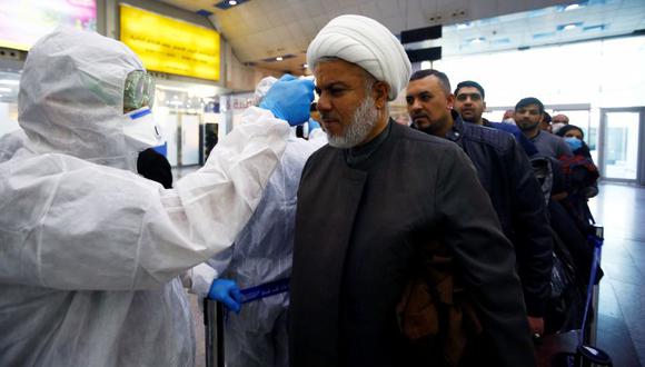 El personal médico iraquí verifica la temperatura de los pasajeros, en medio del nuevo brote de coronavirus, a su llegada al aeropuerto de Najaf, Irak. (Foto: AFP).