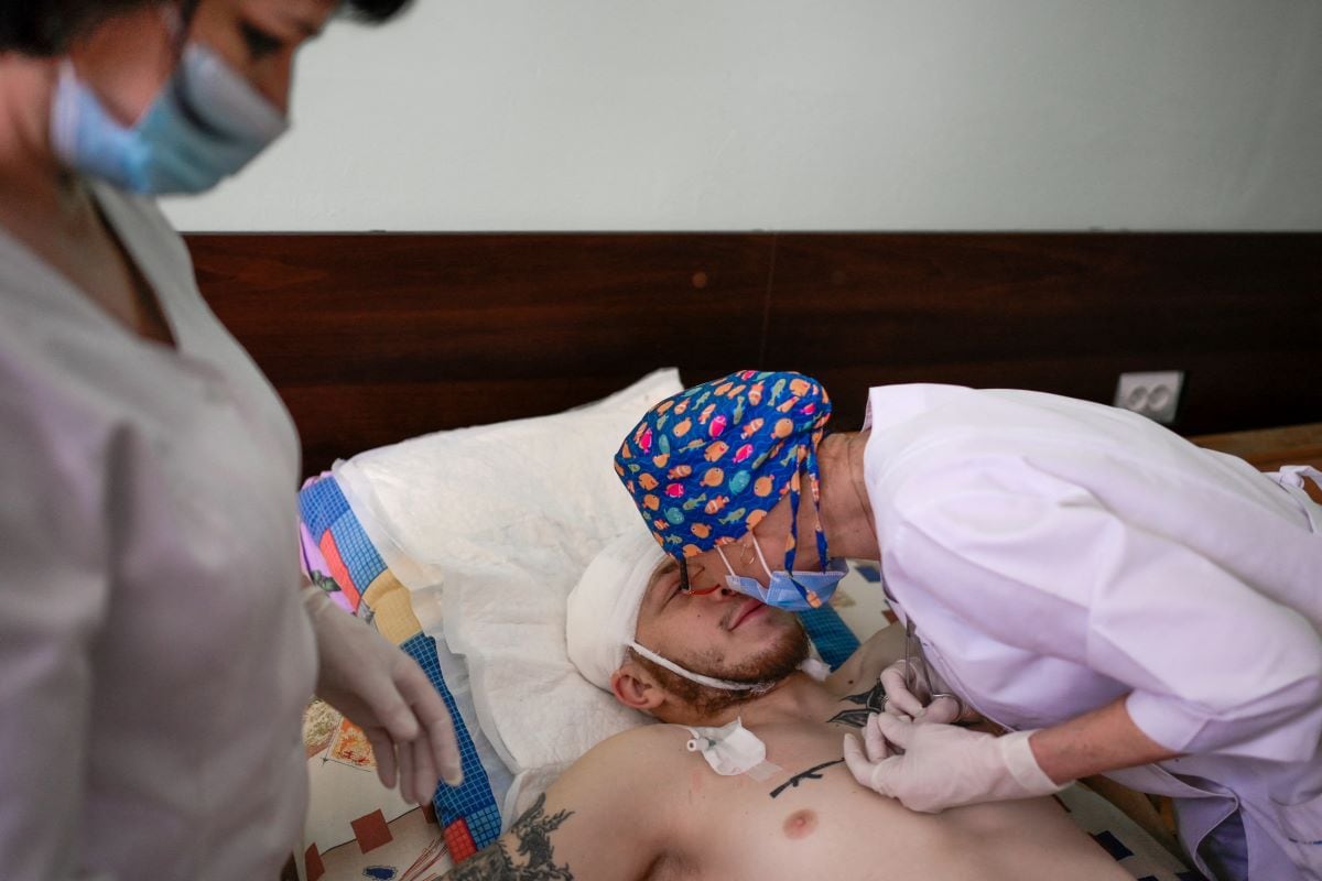 A Ukrainian soldier is comforted by a nurse while receiving treatment at the central hospital in Mykolaiv, 100 km from Odessa, in western Ukraine, on March 8, 2022. (BULENT KILIC / AFP)